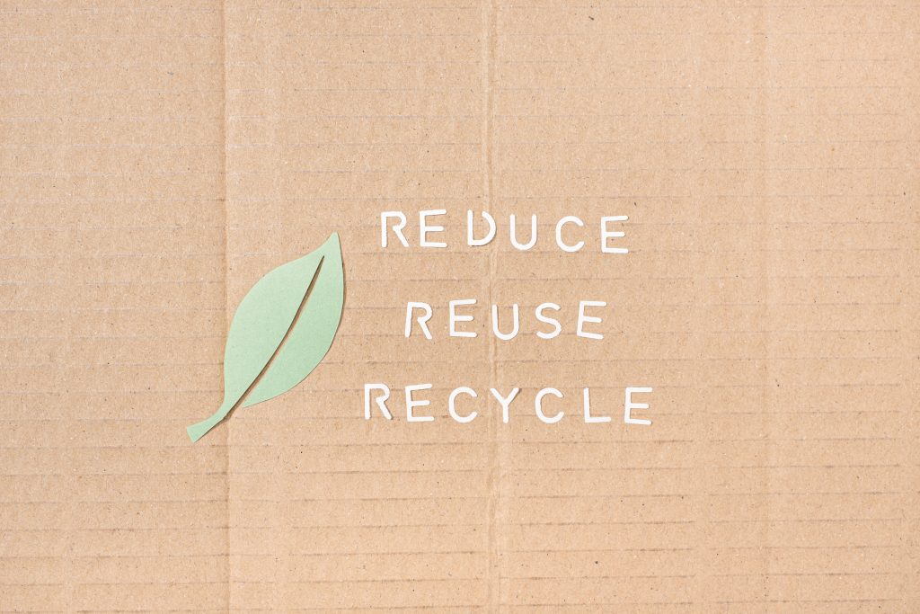 Kartonschild mit der Aufschrift: Reduziere, wiederverwenden und recyceln